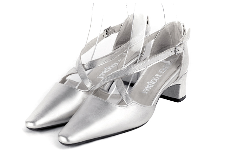 Silver open side elegant shoes, with crossed straps. Tapered toe. Low kitten heels.